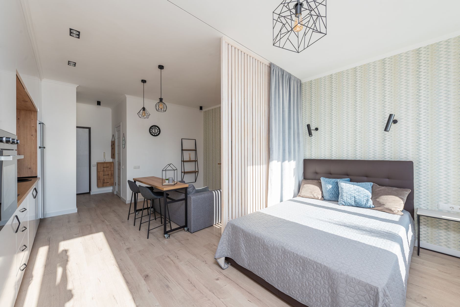 A studio apartment where the bed, a sofa and a small kitchen share one room