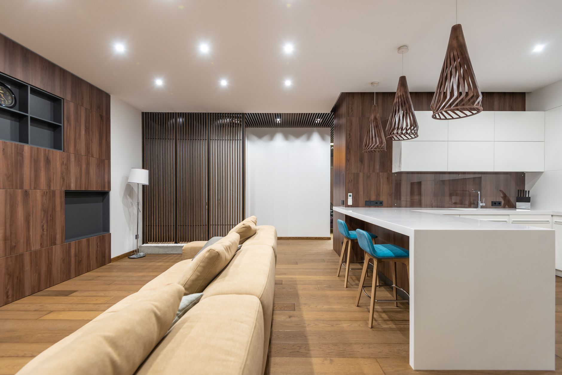 A long white kitchen island with two bar stools tucked along its side, sharing one open room with the sofa