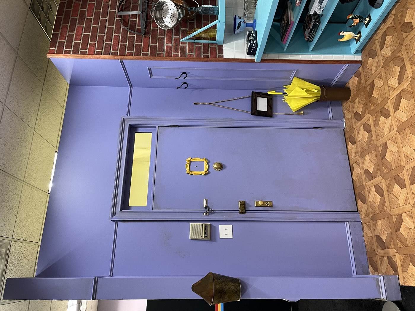 The purple front door of the Monica's apartment set recreation seen from inside, with the small table beside the door and the open space beyond it.